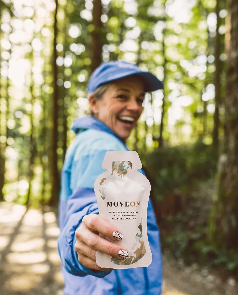 A woman holding a MoveOn sachet on a forest trail